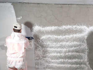 Fachhandwerker trägt StoPox WB 50 auf Betonwand auf