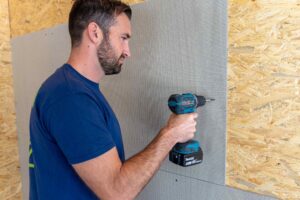 Handwerker mit Akku-Schrauber befestigt VeroBoard AllStar auf Holzlattung.