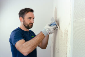 Handwerker trägt Leicht gekörnten VeroBoard AllStar Kombi-Mörtel an Innenwand auf.