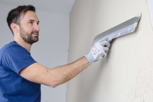 Handwerker streicht den Mörtel an der Innenwand glatt aus.