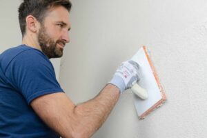 Handwerker filzt den geglätteten Mörtel an der Innenwand ab.