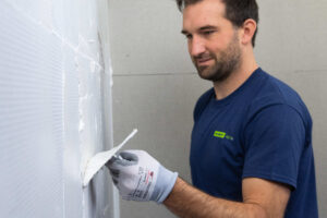 Handwerker bringt VeroBoard AllStar Silikat-Spachtel schichtweise auf für glatte Wandoberflächen.