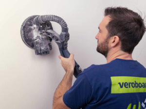 Handwerker schleift Innenwand Oberfläche für gewünschten Glättegrad.