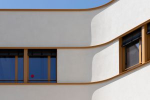 Außenaufnahme von abgerundeter Gebäudecke: Die neue Schule „Collège Claudine Hermann in Massy, südlich von Paris, ist ein Neubau mit hohem Anspruch: Mit einem U-Wert von 0,15 W/m²K sind die Wände hochdämmend, zugleich zeigt sich der Neubau auch besonders attraktiv gestaltet. Die helle, fugenlose Putzfassade ist auch an den gerundeten Innen- und Außenecken von höchster handwerklicher Qualität.