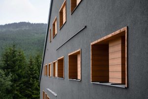 Außenaufnahme von Haus mit dunkler Fassade: Eine gute Dämmung schützt Häuser nicht nur vor Wärmever-lusten im Winter, sondern auch vor sommerlicher Hitze. Wer eine dunkle Fassade wählt, sollte auf Spezial-Fassadenfarben wie „StoColor X-black“ setzen, die sich durch Nah-Infrarot-Reflek¬toren nicht so stark aufheizen wie konventionelle Alternativen.