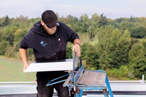 Handwerker beim Abkanten. Montage der Rechteckspeier: Der Flansch wird bauseits auf die berechnete Höhe abgekantet. Die Attika wird geöffnet – mit einfachen, geraden Schnitten.