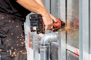 Arbeitsschritt: Aufschneiden der Attika. Montage der Rechteckspeier: Der Flansch wird bauseits auf die berechnete Höhe abgekantet. Die Attika wird geöffnet – mit einfachen, geraden Schnitten.