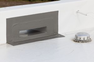 Handwerker beim nächsten Bauschritt auf dem Flachdach: Dann wird der Speier einfach durch die Öffnung gesteckt.