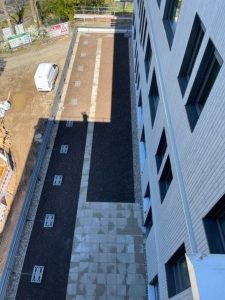 Aufnahme an der Gebäudefassade entlang: Das Erdgeschoss ist zum Teil aus dem Baukörper heraus-gezogen.