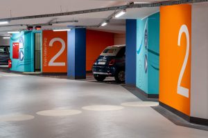 Tiefgarage mit farbigen Wänden und Bodenmarkierungen.
Typischer Bau, der regelmäßig zu inspizieren ist: Eine Tiefgarage ist aufgrund ihrer Nutzung besonders hohen Belastungen ausgesetzt.