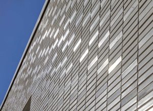 Außenaufnahme der Klinkerfassade des Sportlerhaus in HafenCity Hamburg. Die Fassade erzeugt durch die Neigungswechsel eine subtile Reflexion des Lichts ohne erkennbares Muster.
