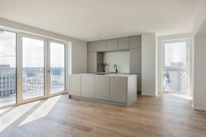 Innenaufnahme von Wohnung im Obergeschoss mit hohen Fenstern. Die Wohnküche ist mit großen Fenstern ausgestattet, ihre Lage ist in der Fassade ablesbar.