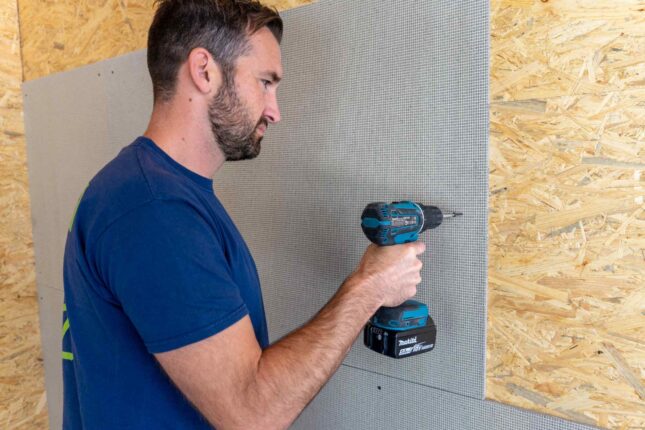 Handwerker mit Akku-Schrauber befestigt VeroBoard AllStar auf Holzlattung.