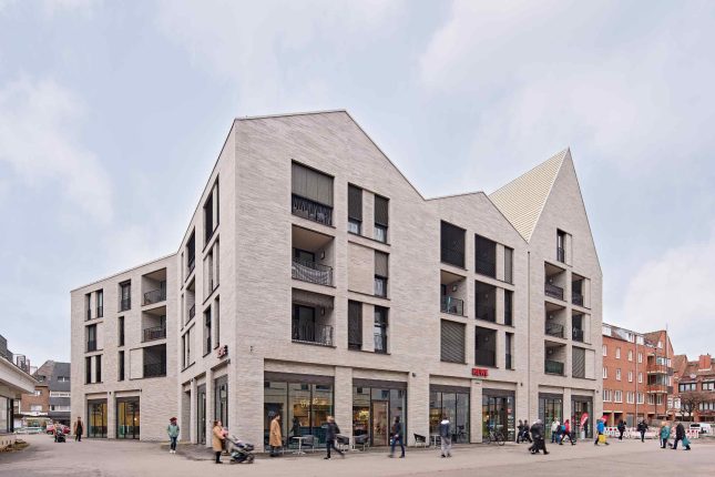 Gebäudeabbildung, Architekturforo: Die Satteldächer mit variierenden Firsthöhen unterstreichen den Eindruck eines aus mehreren Gebäuden gefügten Stadtblocks. Die zurückgesetzten Klinkerflächen sind um die Fenster und eingeschnittenen Loggien angeordnet.