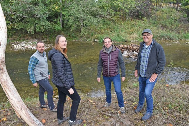 Gruppenbild mit vier Personen am Ufer der Wutach. Ortstermin an der Wutach mit den neuen Einbauten. Von links: Malte Glück, Erster Vorstand Fischereiverein Oberes Wutachtal e.V.; Anica Scharf, Nachhaltigkeitsmanagerin Sto SE & Co. KGaA; Dr. Eike Messow, Leiter Nachhaltigkeit Sto SE & Co. KGaA; Christoph Dörflinger, Regierungspräsidium Freiburg, zuständiger Flussmeister für die Wutach.